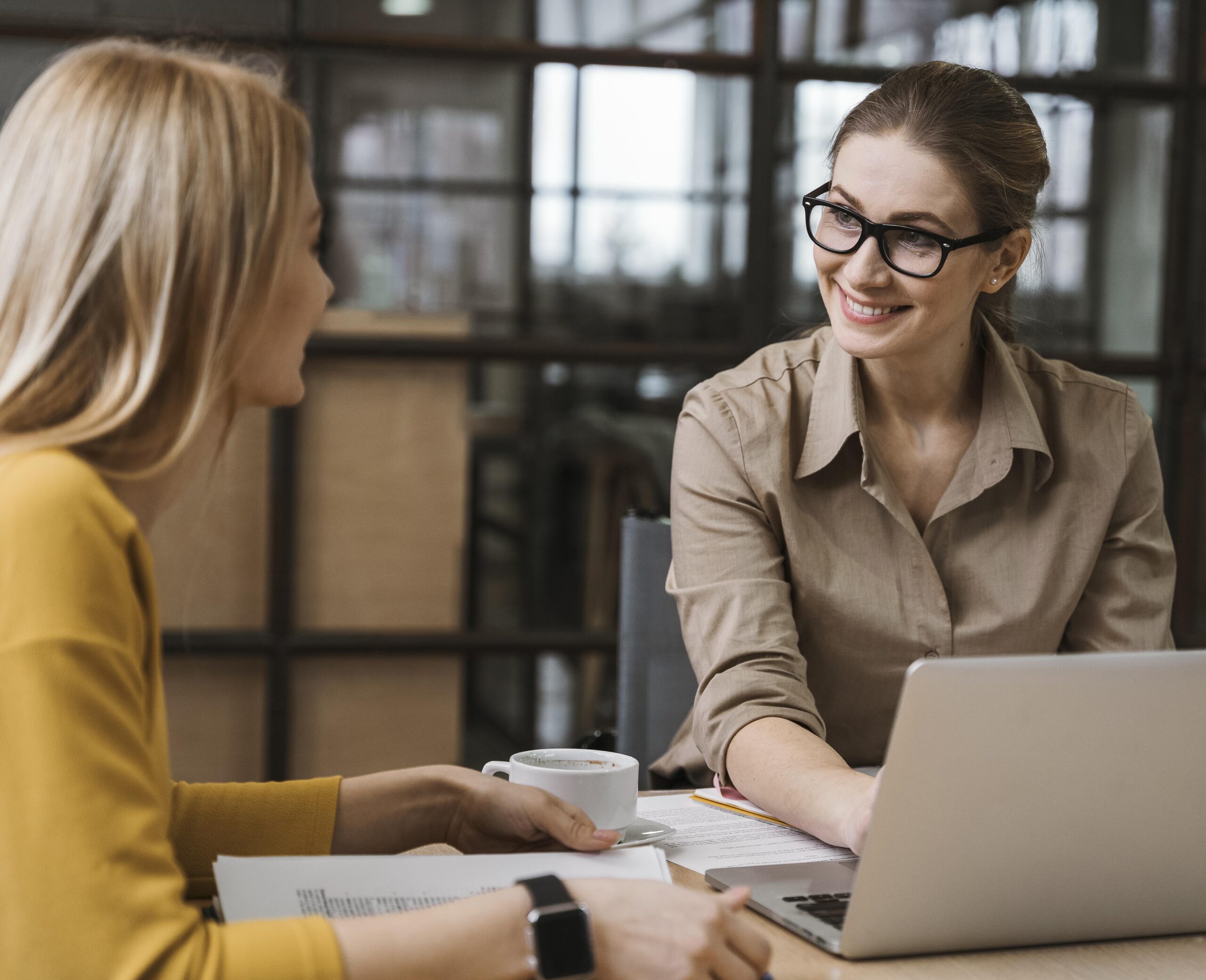 smiley geschaftsfrauen die mit laptop am schreibtisch arbeiten